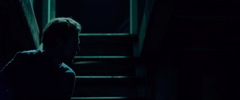 Movie still from “Siberia” (2020), directed by Abel Ferrara – A man standing in front of some steps at night; Medium shot, Low angle