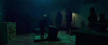Movie still from “Siberia” (2020), directed by Abel Ferrara – A group of people standing in a dark room; Wide shot, High angle