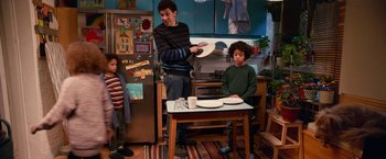 Movie still from “A Boy Called Christmas” (2021), directed by Gil Kenan – A man and two children in a kitchen with a table; Medium shot, Over the shoulder angle