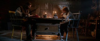 Movie still from “A Boy Called Christmas” (2021), directed by Gil Kenan – Two people sitting at a table with candles on top of it; Wide shot, High angle