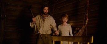 Movie still from “A Boy Called Christmas” (2021), directed by Gil Kenan – A man and a boy holding hands while standing next to each other; Medium shot, Low angle