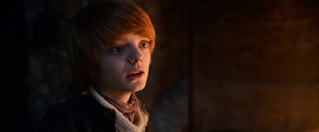 Movie still from “A Boy Called Christmas” (2021), directed by Gil Kenan – A young boy with red hair and a scarf around his neck stares into the camera; Close Up shot, Low angle