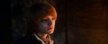Movie still from “A Boy Called Christmas” (2021), directed by Gil Kenan – A boy with red hair is looking at the camera; Close Up shot, Low angle