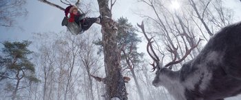 Movie still from “A Boy Called Christmas” (2021), directed by Gil Kenan – A person on a rope swing next to a tree; Wide shot, Low angle