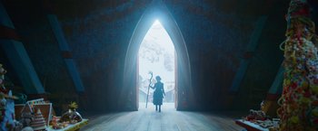 Movie still from “A Boy Called Christmas” (2021), directed by Gil Kenan – A person holding a staff in front of an archway; Wide shot, Low angle