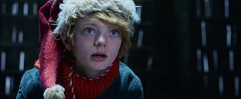 Movie still from “A Boy Called Christmas” (2021), directed by Gil Kenan – A young boy wearing a hat and a scarf; Close Up shot, Low angle