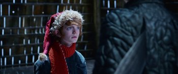 Movie still from “A Boy Called Christmas” (2021), directed by Gil Kenan – A young man wearing a red scarf and a red hat; Close Up shot, Over the shoulder angle
