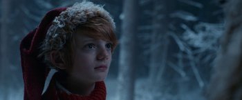 Movie still from “A Boy Called Christmas” (2021), directed by Gil Kenan – A young boy with red hair wearing a red sweater; Close Up shot, Low angle