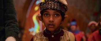 Movie still from “A Boy Called Christmas” (2021), directed by Gil Kenan – A young boy wearing a hat and a costume; Close Up shot, High angle