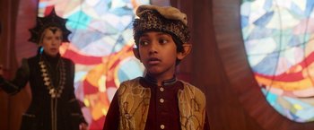 Movie still from “A Boy Called Christmas” (2021), directed by Gil Kenan – A young boy dressed as a elf in front of a stained glass window; Close Up shot, Over the shoulder angle