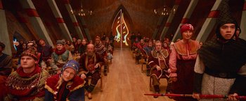 Movie still from “A Boy Called Christmas” (2021), directed by Gil Kenan – A group of people sitting in chairs in front of a wall with an image on it; Wide shot, High angle