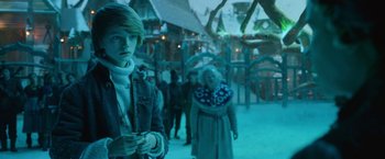 Movie still from “A Boy Called Christmas” (2021), directed by Gil Kenan – A man standing next to a crowd of people in a building; Medium shot, Low angle