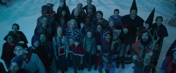 Movie still from “A Boy Called Christmas” (2021), directed by Gil Kenan – A group of people standing together in a room; Wide shot, High angle