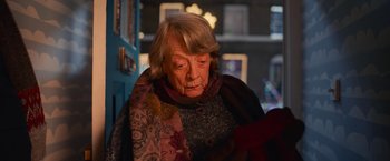 Movie still from “A Boy Called Christmas” (2021), directed by Gil Kenan – An older woman wearing a colorful scarf looking down; Close Up shot, Over the shoulder angle