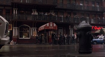 Movie still from “Sid and Nancy” (1986), directed by Alex Cox – A group of people standing outside of a building; Wide shot, Low angle