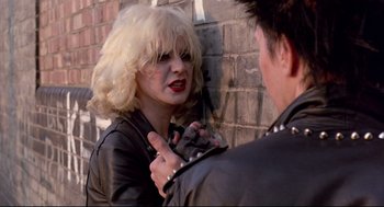 Movie still from “Sid and Nancy” (1986), directed by Alex Cox – A woman in a leather jacket is talking to a man in a leather jacket; Close Up shot, Over the shoulder angle