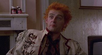 Movie still from “Sid and Nancy” (1986), directed by Alex Cox – A man with red hair is wearing chains; Close Up shot, Low angle