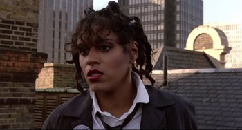 Movie still from “Sid and Nancy” (1986), directed by Alex Cox – A woman with curly black hair and red lipstick; Close Up shot, Low angle