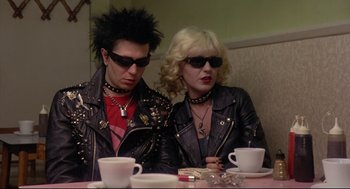 Movie still from “Sid and Nancy” (1986), directed by Alex Cox – A man and a woman sitting at a dinner table; Medium shot, Over the shoulder angle