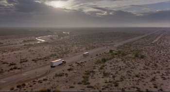 Movie still from “Sid and Nancy” (1986), directed by Alex Cox – Two buses are driving down a dirt road in the middle of the desert; Extreme Wide shot, High angle