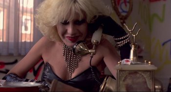 Movie still from “Sid and Nancy” (1986), directed by Alex Cox – A woman with blonde hair talking on a phone; Close Up shot, Low angle