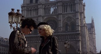 Movie still from “Sid and Nancy” (1986), directed by Alex Cox – A man and a woman walking in front of a building; Medium shot, Low angle