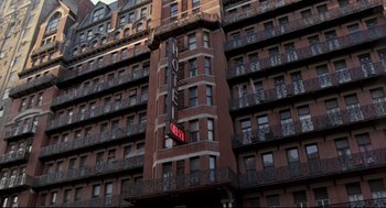 Movie still from “Sid and Nancy” (1986), directed by Alex Cox – A hotel sign is on the side of a building; Wide shot, Low angle