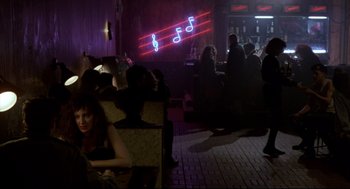 Movie still from “Sid and Nancy” (1986), directed by Alex Cox – People are sitting at a bar with a neon sign; Wide shot, Over the shoulder angle