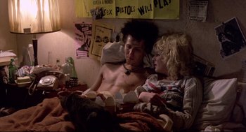 Movie still from “Sid and Nancy” (1986), directed by Alex Cox – A man and a woman laying in a bed together; Medium shot, Low angle