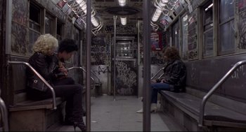 Movie still from “Sid and Nancy” (1986), directed by Alex Cox – Two people are sitting on a subway train; Wide shot, High angle