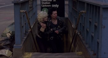 Movie still from “Sid and Nancy” (1986), directed by Alex Cox – A man and a woman are standing on a train platform; Wide shot, Low angle