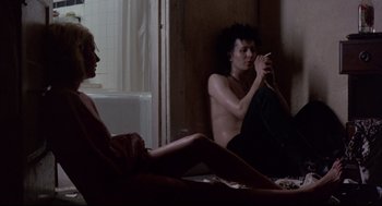 Movie still from “Sid and Nancy” (1986), directed by Alex Cox – A man and a woman sitting in a bathroom; Medium shot, Low angle