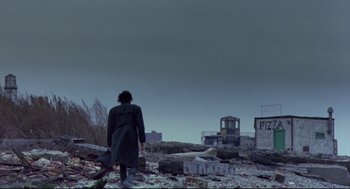Movie still from “Sid and Nancy” (1986), directed by Alex Cox – A person standing in the middle of a lot of rubble; Wide shot, Low angle