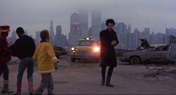 Movie still from “Sid and Nancy” (1986), directed by Alex Cox – A man and a child in front of a taxi cab in a city; Wide shot, Over the shoulder angle