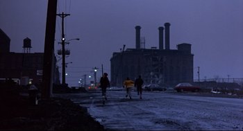 Movie still from “Sid and Nancy” (1986), directed by Alex Cox – A group of people walking down a street at night; Extreme Wide shot, Low angle