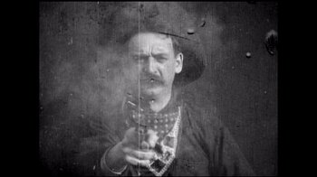 Movie still from “Side by Side” (2012), directed by Christopher Kenneally – An old photo of a man holding a gun; Medium shot, Low angle