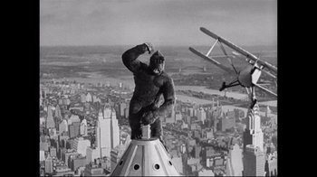 Movie still from “Side by Side” (2012), directed by Christopher Kenneally – A man standing on top of a building with an airplane in the background; Wide shot, Low angle