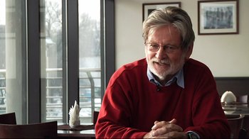 Movie still from “Side by Side” (2012), directed by Christopher Kenneally – An older man sitting at a table in front of a window; Close Up shot, Over the shoulder angle