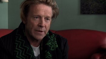 Movie still from “Side by Side” (2012), directed by Christopher Kenneally – A person wearing a scarf on a couch; Close Up shot, Over the shoulder angle