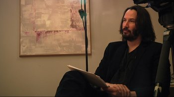 Movie still from “Side by Side” (2012), directed by Christopher Kenneally – A man sitting on a couch holding a tablet; Close Up shot, Over the shoulder angle