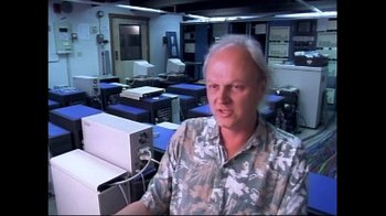Movie still from “Side by Side” (2012), directed by Christopher Kenneally – A man standing in front of computers in a room; Medium shot, High angle