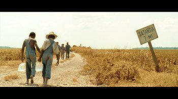 Movie still from “Side by Side” (2012), directed by Christopher Kenneally – A group of people walking down a dirt road; Extreme Wide shot, Low angle