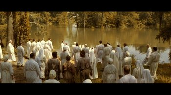 Movie still from “Side by Side” (2012), directed by Christopher Kenneally – A group of people standing in front of a body of water; Extreme Wide shot, High angle