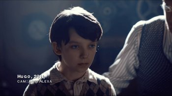 Movie still from “Side by Side” (2012), directed by Christopher Kenneally – A young boy wearing a striped shirt and a sweater; Close Up shot, Over the shoulder angle