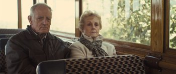 Movie still from “Sightseers” (2012), directed by Ben Wheatley – An older woman sitting on a bench looking out the window; Close Up shot, Over the shoulder angle