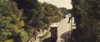 Movie still from “Sightseers” (2012), directed by Ben Wheatley – A red and white tram is on the tracks near a forest; Extreme Wide shot, High angle