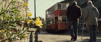 Movie still from “Sightseers” (2012), directed by Ben Wheatley – A red and yellow double - decker bus on the side of the road; Wide shot, Low angle