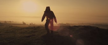 Movie still from “Sightseers” (2012), directed by Ben Wheatley – A person standing on a hill at sunset; Wide shot, Low angle