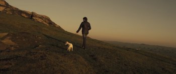 Movie still from “Sightseers” (2012), directed by Ben Wheatley – A person and a dog are standing on a grassy hill; Wide shot, Low angle