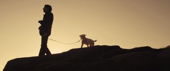 Movie still from “Sightseers” (2012), directed by Ben Wheatley – A small white dog is on a leash on a hill; Wide shot, Low angle